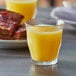 A Duralex Picardie glass of orange juice next to a plate of toast.