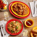 A table with Acopa Capri passion fruit red stoneware plates of food and a glass of wine.