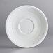 An Acopa Capri white stoneware saucer with a circular pattern on a gray surface.