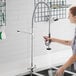 A woman using a deck mount low lead pre-rinse faucet to wash dishes in a professional kitchen.