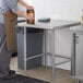 A woman pouring liquid from a jar into a Regency stainless steel work table.