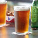 Two Duralex glass tumblers of beer on a table.