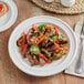 A plate of food with meat and peppers on an Acopa Capri coconut white stoneware plate.
