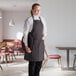 A woman wearing a black and white chalk stripe bib apron with 2 pockets.