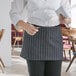 A woman wearing a Choice black and white pinstripe apron with 3 pockets.