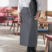 A woman wearing a Choice black and white striped apron holding a tray.