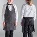 Two women wearing black and white chalk stripe tuxedo aprons.