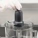 A hand in a glove using a Waring S blade in a food processor.