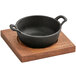 A Valor pre-seasoned cast iron serving bowl on a rustic wooden underliner.