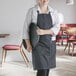 A woman in a Choice black and white pinstripe apron holding a black round tray.