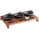 A group of black cast iron pans on a wooden display stand.