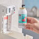 A hand holding a Rubbermaid Microburst 3000 cucumber melon air freshener refill can.