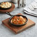 A Valor pre-seasoned mini cast iron skillet of food on a wooden board with a fork.