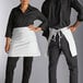 A man and woman wearing white aprons standing next to each other on a counter.