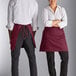 A man and woman wearing maroon Choice half bistro aprons with pockets.