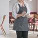 A woman wearing a Choice black and white striped bib apron with 3 pockets.