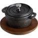 A Valor pre-seasoned black cast iron pot on a Rustic Chestnut Finish Rubberwood plate.