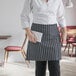 A woman wearing a black and white chalk stripe half bistro apron with pockets.