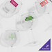 A close-up of a clear Tritan plastic balloon wine glass with a green custom label.
