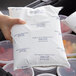 A hand holding a white package of Polar Tech Ice Brix in a cooler.