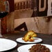 A white Front of the House porcelain plate with food on it on a table.