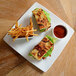 A white square porcelain plate topped with a sandwich, fries, and lettuce.