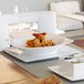 A white square porcelain plate with food on it.
