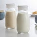 Two Anchor Hocking milk bottles on a table with a glass of milk.