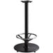 A Lancaster Table & Seating black cast iron bar height table base with a foot rest and self-leveling feet.