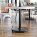 A Lancaster Table & Seating cast iron table base with a table and chairs in a hospital cafeteria.