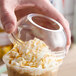 A hand holding a Dart clear plastic cup with a dome lid over a drink.