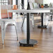 A Lancaster Table & Seating cast iron table base with chairs and a laptop on it.