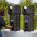 A woman using a black Cambro handwashing station to fill a water bottle.