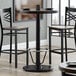 A Lancaster Table & Seating bar height table with chairs and a foot rest.