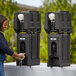 A woman washing her hands in a black plastic container with a white label.