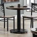 A table with a Lancaster Table & Seating cast iron table base and two chairs.