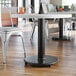 A Lancaster Table & Seating cast iron table base with FLAT Tech levelers on a table in a restaurant dining area.