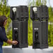 A woman using the black Cambro portable handwash station to wash her hands.