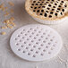 A white Fox Run lattice pie crust cutter on a white background over a pie with a lattice pattern.