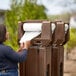 A woman using a Cambro brown portable handwash station to put a roll of paper towels on the dispenser.