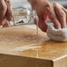 A hand pouring Fox Run Gourmet Butcher Block Oil into a small bottle.