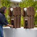 A woman using a brown Cambro portable handwash station to wash her hands with soap.