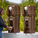 A woman washing her hands in a brown plastic Cambro handwash station.