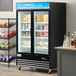 An Avantco black glass door merchandiser freezer filled with food.