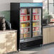 An Avantco swing glass door freezer with LED lighting full of boxed food.