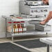 A man using a Regency stainless steel equipment stand in a professional kitchen to prepare food.