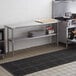 A woman opens a box to reveal a Regency stainless steel work table with undershelf.