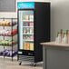 An Avantco black swing glass door merchandiser freezer with food in it.