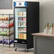 An Avantco black swing glass door merchandiser freezer with LED lighting.