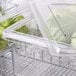 A white plastic Cambro food storage container filled with green apples.